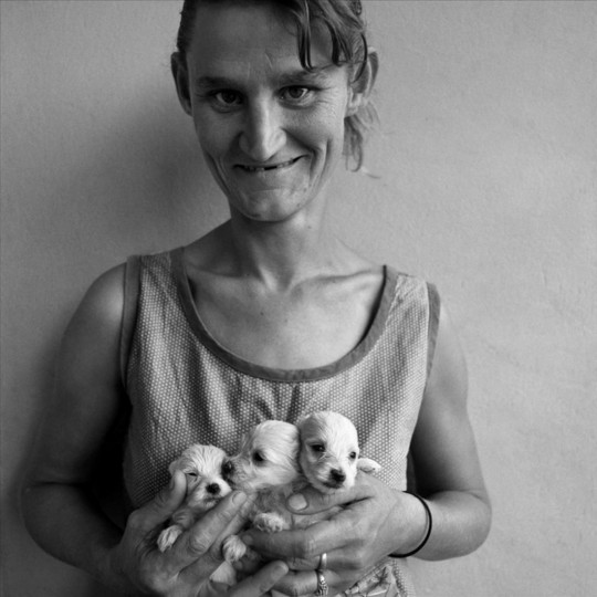 Roger Ballen, wife of abattoir worker holding three puppies