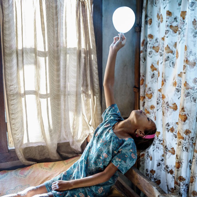 Phida, 9 years old, is playing with a balloon in her bedroom