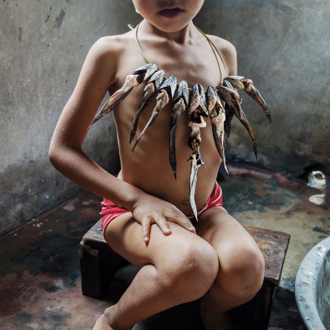 Grace wearing a string of dried fish as a necklace